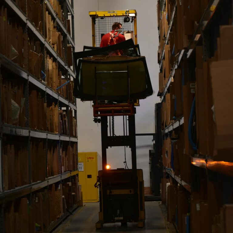 Auto Parts Warehouse Worker with Windshields on a Forklift